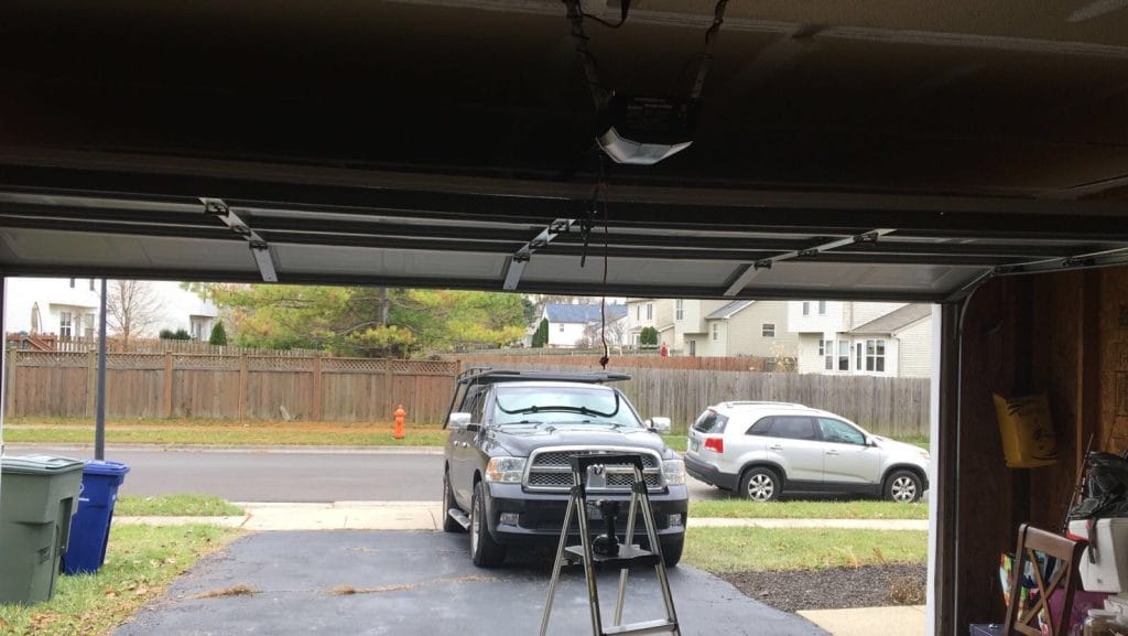 View from inside a garage with the door open and a vehicle parked in the driveway